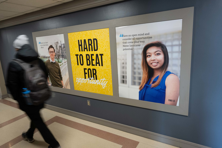 student walking by a branded wall display